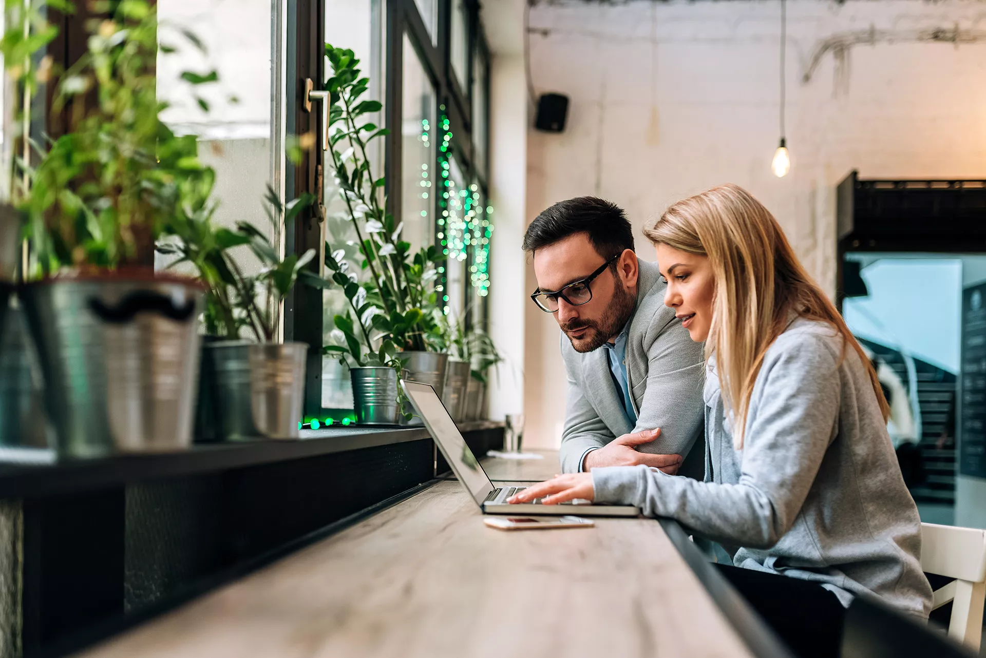 Mann und Frau sitzen in einem Büro und arbeiten an einem Laptop